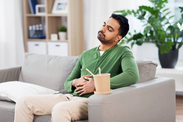 Hombre indio complacido comiendo comida para llevar en casa — Foto de Stock