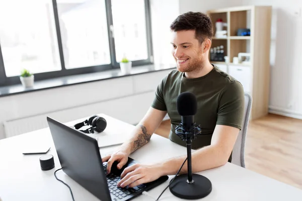Muž s přenosným počítačem a mikrofonem v domácí kanceláři — Stock fotografie