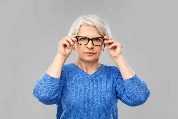 Ritratto di donna anziana in occhiali sopra grigio — Foto Stock