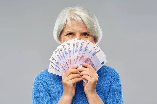 Senior vrouw met honderden eurobankbiljetten — Stockfoto