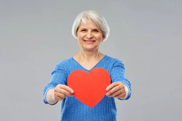 Donna anziana sorridente con cuore rosso — Foto Stock