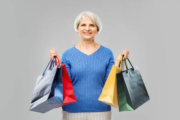 Senior vrouw met boodschappentassen over grijs — Stockfoto