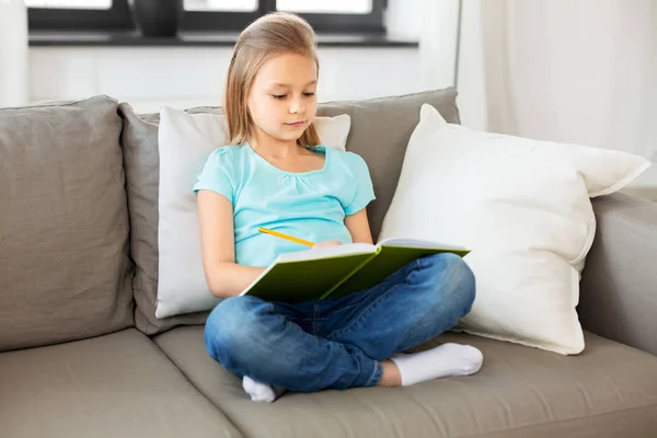 Kleines Mädchen mit Tagebuch sitzt zu Hause auf Sofa — Stockfoto