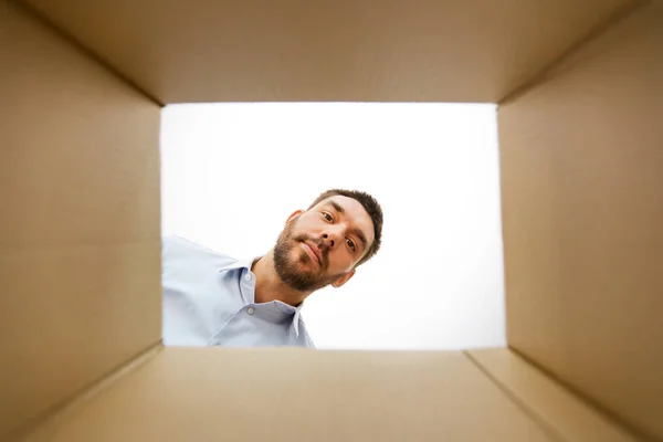 Чоловік дивиться у відкриту коробку посилок — стокове фото