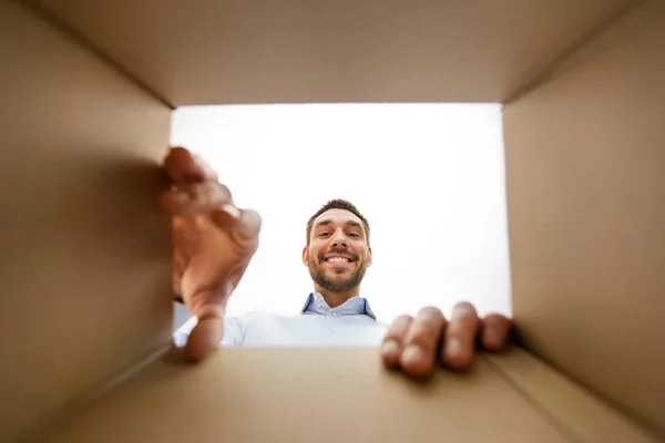 Χαμογελαστός άνθρωπος παίρνοντας κάτι από το κουτί δεμάτων — Φωτογραφία Αρχείου