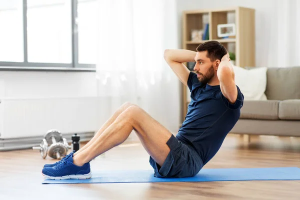 Hombre haciendo ejercicios abdominales en casa —  Fotos de Stock