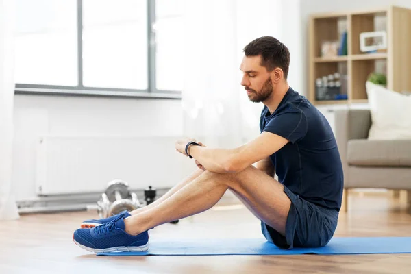 Hombre con rastreador de fitness haciendo ejercicio en casa —  Fotos de Stock