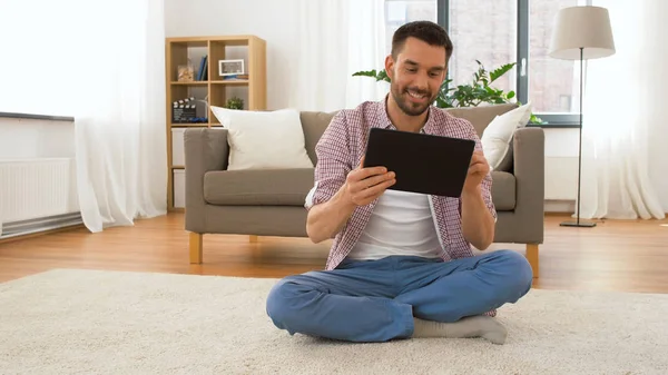 Sonriente hombre usando tableta ordenador en casa —  Fotos de Stock