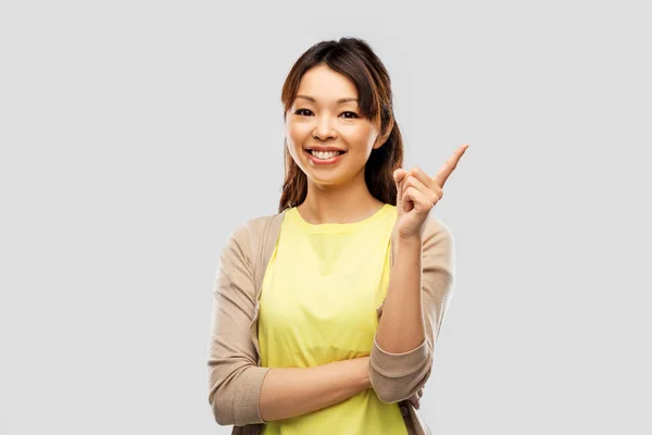 Feliz asiático mujer apuntando dedo arriba — Foto de Stock