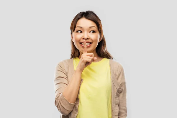Šťastná asijská žena s prstem na rtech — Stock fotografie
