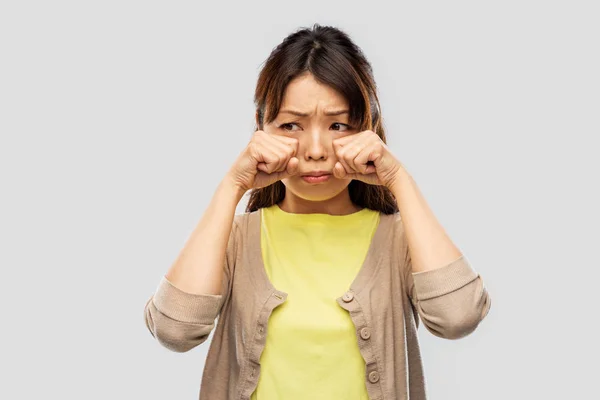 Triste asiático mujer llorando sobre gris fondo —  Fotos de Stock
