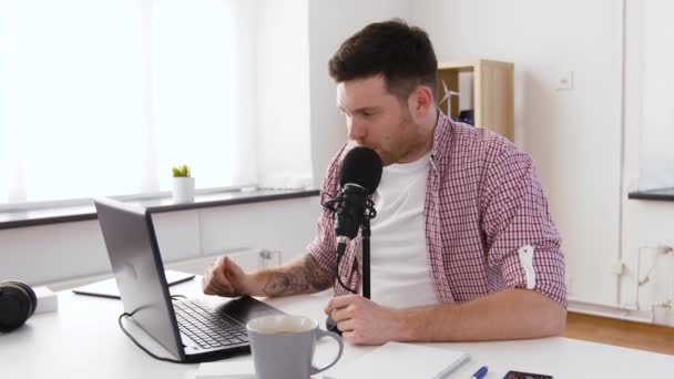 Счастливый молодой человек с ноутбуком и микрофоном дома — стоковое видео