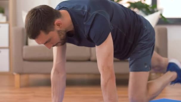 Мужчина делает беговые упражнения на доске дома — стоковое видео
