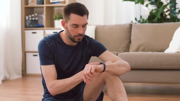 Hombre con rastreador de fitness beber agua en casa — Vídeos de Stock