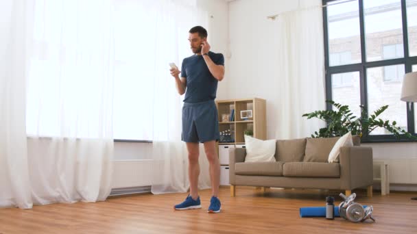 Man with wireless earphones exercising at home — Stock Video