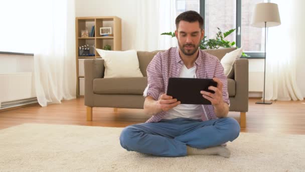 Мужчина с планшетным компьютером медитирует дома — стоковое видео