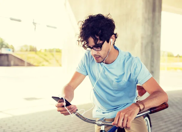 Uomo con smartphone e auricolari in bicicletta — Foto Stock