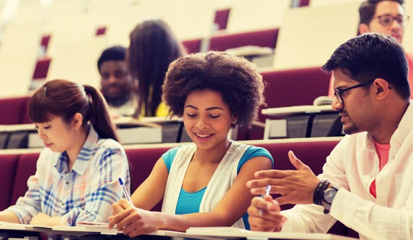 Grupo de estudiantes con cuadernos en la sala de conferencias — Foto de Stock