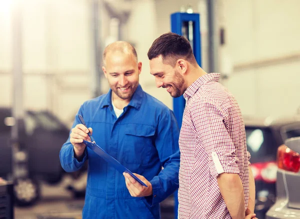 Automechaniker mit Klemmbrett und Mann im Autohaus — Stockfoto