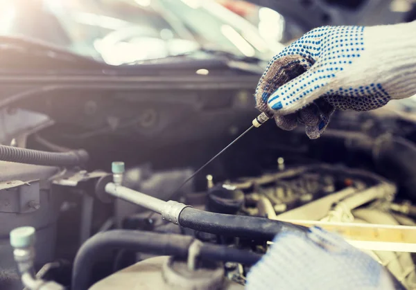 Mecânico com dipstick verificando o nível de óleo do motor — Fotografia de Stock