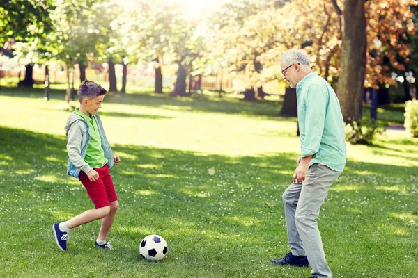 Старик и мальчик играют в футбол в летнем парке — стоковое фото