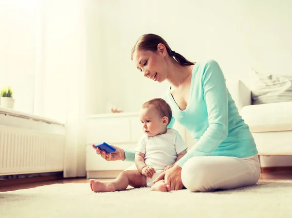행복 한 어머니가 집에서 아기에게 스마트폰을 보여 주는 모습 — 스톡 사진