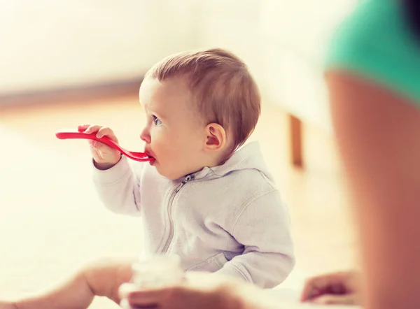 Madre y bebé con cuchara comiendo en casa — Foto de Stock