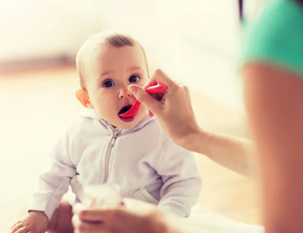 Mother with spoon feeding little baby at home — Stock Photo, Image