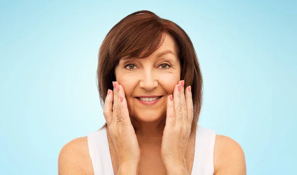 Ritratto di una donna anziana sorridente che si tocca il viso — Foto Stock