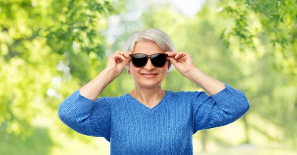 Glimlachende senior vrouw in zwart zonnebril — Stockfoto