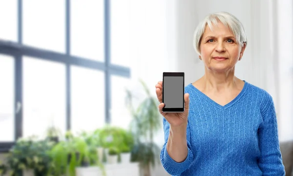 Senior vrouw toont smartphone thuis — Stockfoto