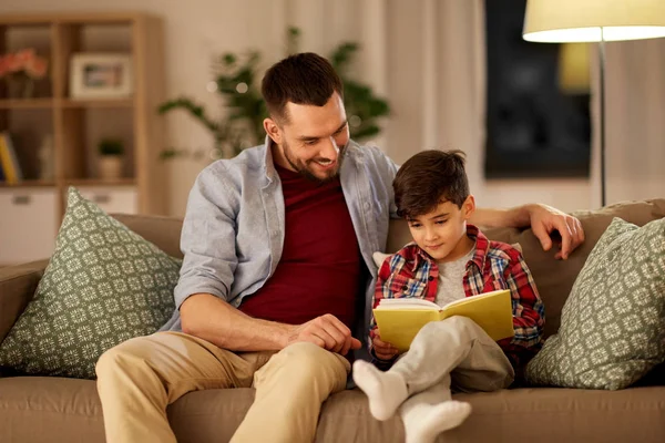 Feliz padre e hijo leyendo libro sofá en casa —  Fotos de Stock