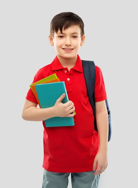 Menino de escola sorrindo com livros e bolsa de escola — Fotografia de Stock