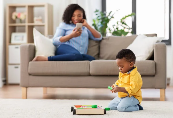 Bebek oyuncak blokları ve akıllı telefon ile anne oynuyor — Stok fotoğraf