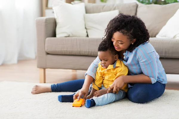 Mãe e bebê brincando com carro de brinquedo em casa — Fotografia de Stock