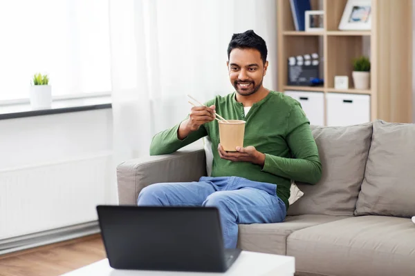 Indio hombre con portátil comer comida para llevar en casa — Foto de Stock