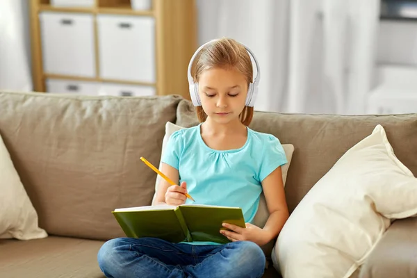 Mädchen mit Kopfhörer und Tagebuch zu Hause auf dem Sofa — Stockfoto