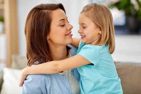 Hija pequeña abrazando a su madre en el sofá en casa — Foto de Stock