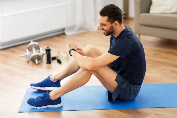 Hombre sonriente con rastreador de fitness haciendo ejercicio en casa —  Fotos de Stock