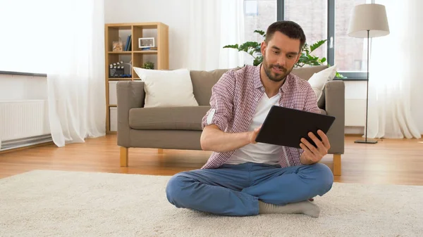Usmívající se muž používající tabletový počítač doma — Stock fotografie