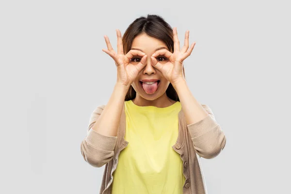 Glimlachende aziatische vrouw kijken door vinger bril — Stockfoto