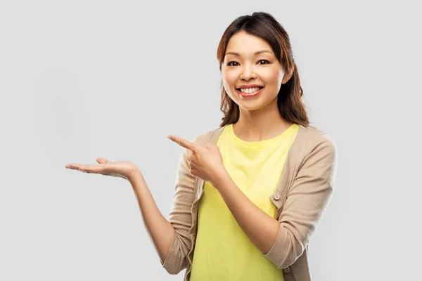 Happy asian woman holding something on hand — Stock Photo, Image