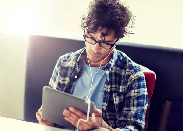 Man met tablet pc en de koptelefoon zit op café — Stockfoto