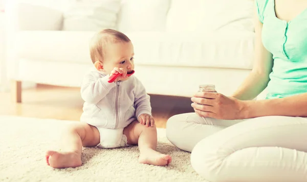 Mother and baby with spoon eating puree at home — Stock Photo, Image