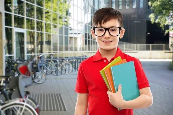 Leende skolpojke i glas med böcker — Stockfoto