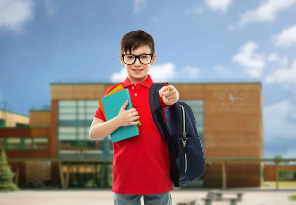 Skolpojke med böcker och väska över skolan — Stockfoto