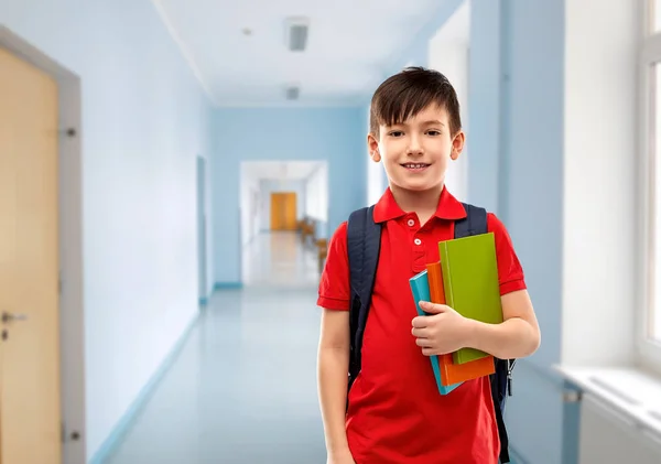 Усміхнений студентський хлопчик з книгами та шкільною сумкою — стокове фото