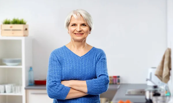 Улыбающаяся пожилая женщина в голубом свитере на кухне — стоковое фото
