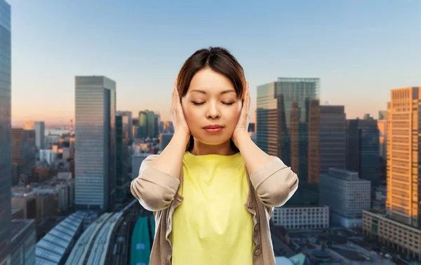 Asiatico donna chiusura orecchie da mani in tokyo città — Foto Stock