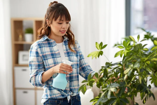 Feliz asiático mujer pulverización houseplant en casa — Foto de Stock